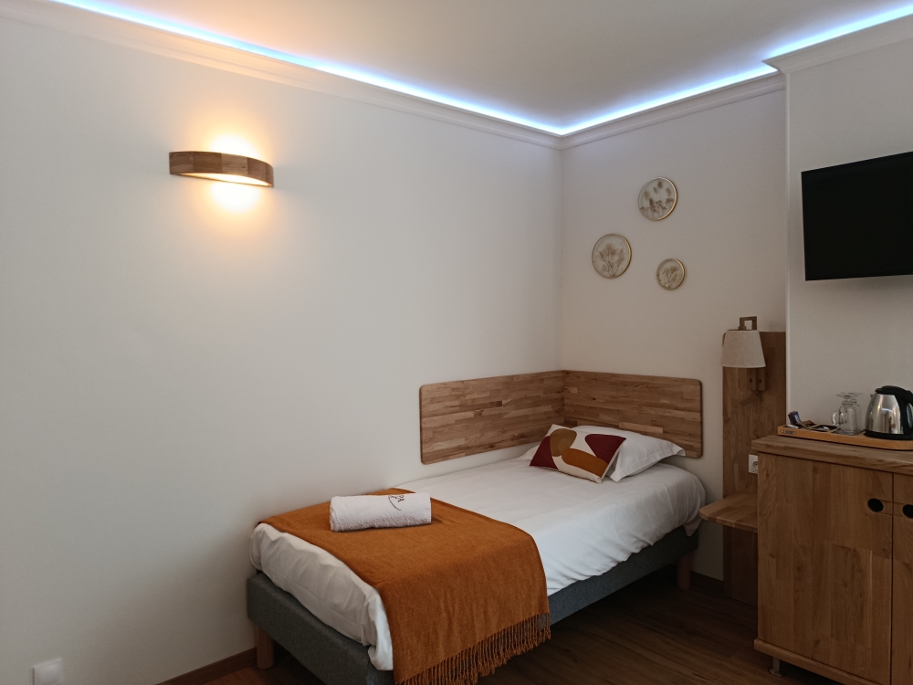 Chambre single, tête de lit bois et éclairage doux